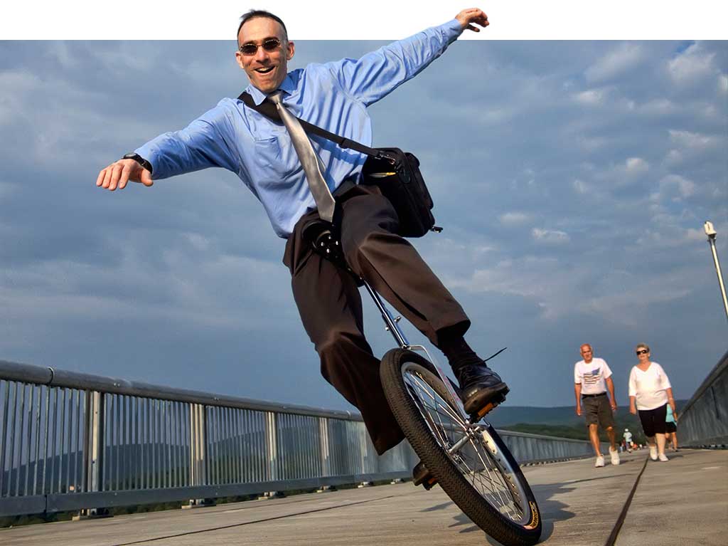 Jordan riding his unicycle with blue sky background
