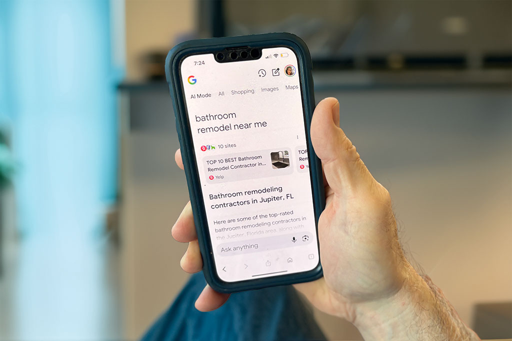 Close-up of smart smartphone in man's hand performing a Google search for bathroom remodeling.
